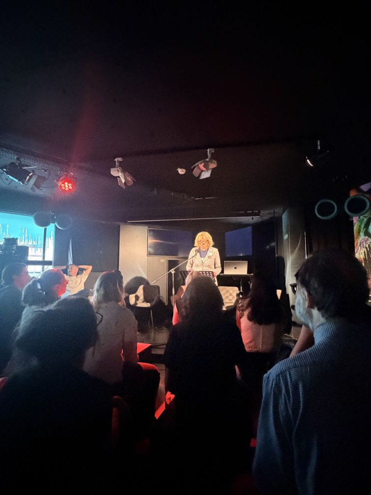 View from the audience at Frankfurt’s Museum of Modern Electronic Music (MOMEM), showing Christiane Wiesenfeldt speaking on stage during the Techno Heritage panel, with atmospheric red and blue lighting.
